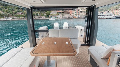ICE 19 Saxdor 400 GTO ICE cockpit lounge with wraparound seating, wooden dining table, and panoramic Dubai Marina skyline views.