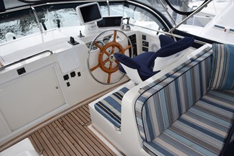 JAMIE LYN 9 1997 Grand Banks Classic yacht helm with striped seating and wooden steering wheel.