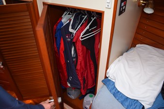 JAMIE LYN 29 Closet with jackets on hangers inside a 1997 Grand Banks Classic boat cabin.