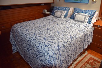 JAMIE LYN 35 Luxurious bedroom in 1997 Grand Banks Classic yacht with elegant blue-patterned bedding.