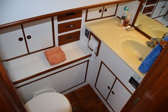 JAMIE LYN 39 Bathroom interior of 1997 Grand Banks Classic yacht with wooden cabinetry and yellow sink.