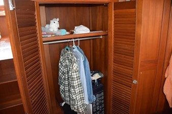 JAMIE LYN 42 Wooden closet interior on a 1997 Grand Banks Classic boat, with hanging clothes and shelves.