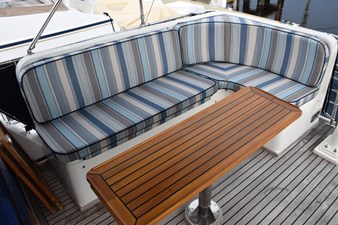 JAMIE LYN 75 Striped seating and wooden table on 1997 Grand Banks Classic yacht deck.