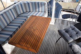 JAMIE LYN 79 Luxurious 1997 Grand Banks Classic yacht deck with striped seating and elegant wooden table.