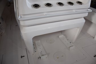 Behind helm seat console, drink holder or rod holders and safety grab railing, cooler chocks beneath.