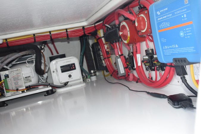 Refrigeration and battery switches and charger under portside helm companion chair.