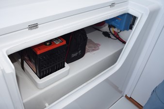 Portside beneath helm level chair, start battery and charger.