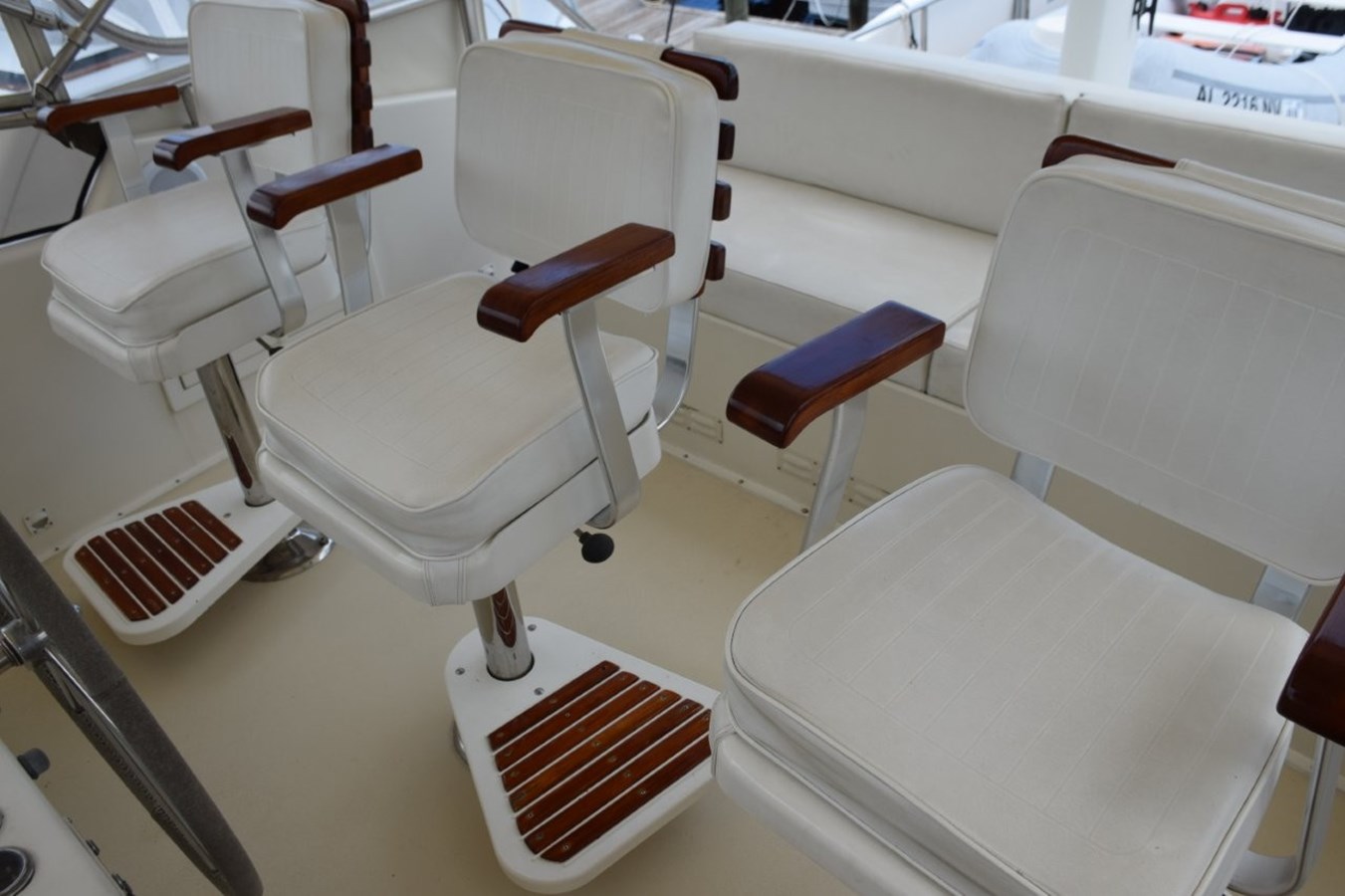 Three teak ladderback chairs with arm and footrests