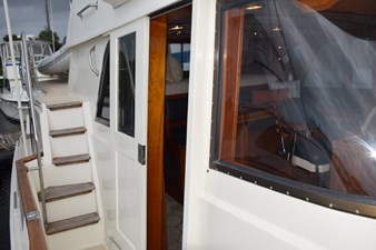 Pilothouse Door and steps up to flybridge. Teak bow rail cap.